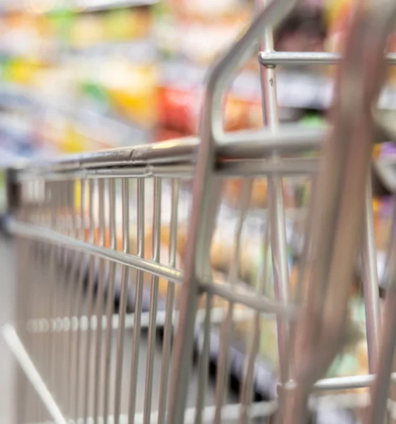 Close up shot of a trolley in a bustling supermarket