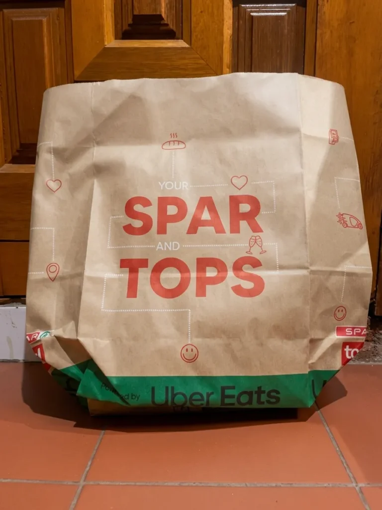 SPAR2U delivery bag delivered to your front door: bag lying in front of a wooden door.