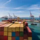 Cape Town harbour with a docked freight ship being loaded with storage containers.