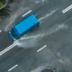 Aerial shot of a blue delivery van driving in a heavy storm.