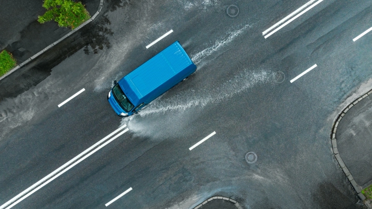Aerial shot of a blue delivery van driving in a heavy storm.