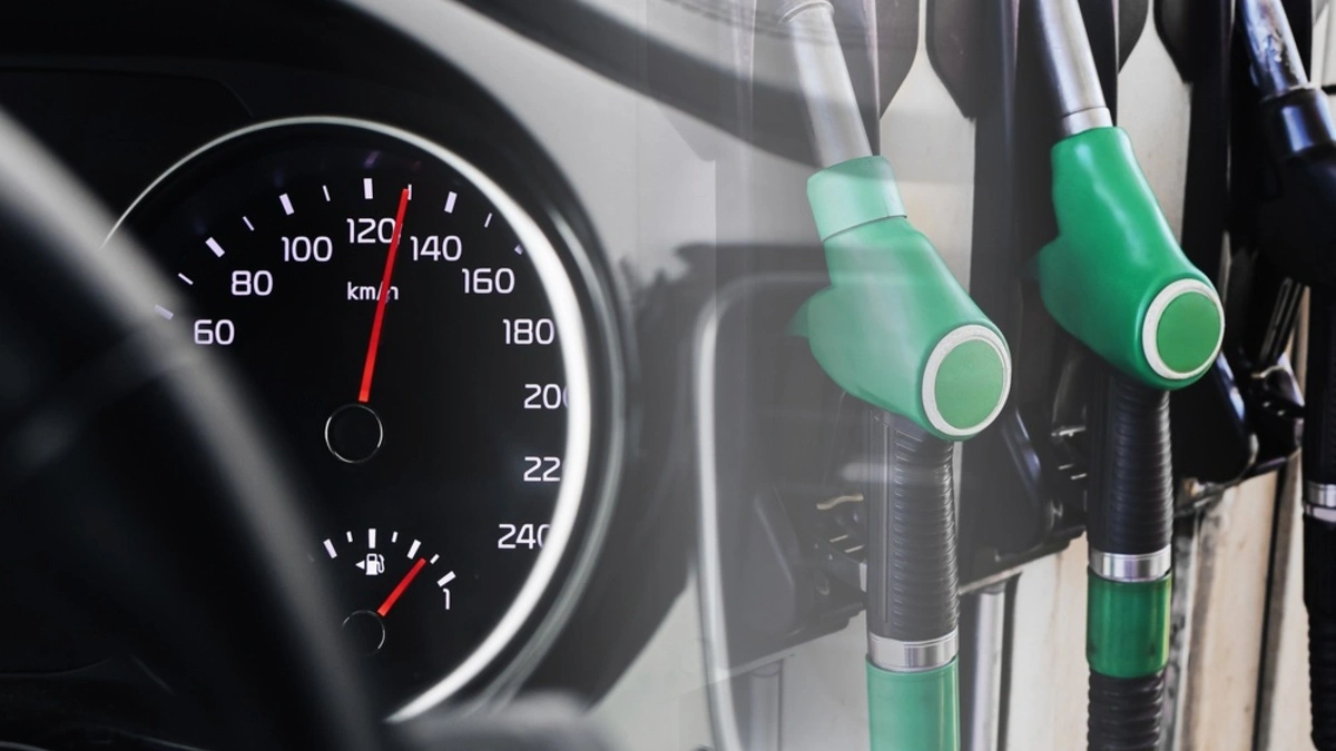 Fuel pomp nozzles beside a car dashboard speedometer showing a full petrol