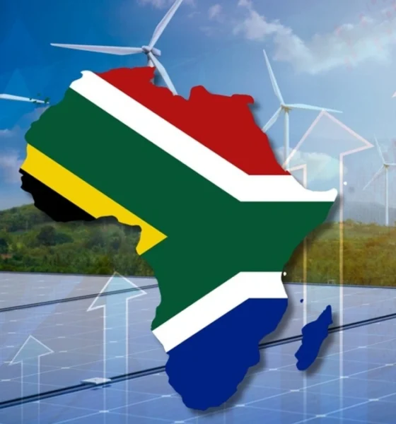 The African continent filled with the South African flag with a backdrop of solar panels and wind turbines.