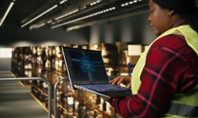 Female warehouse worker using a laptop with an AI tool running the logistics of the warehouse.