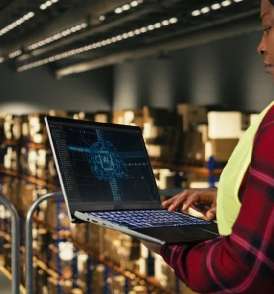 Female warehouse worker using a laptop with an AI tool running the logistics of the warehouse.