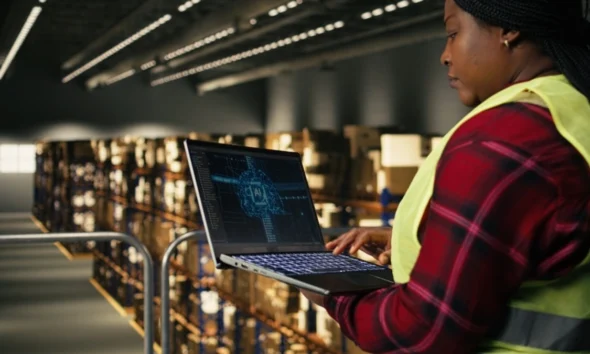 Female warehouse worker using a laptop with an AI tool running the logistics of the warehouse.