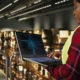 Female warehouse worker using a laptop with an AI tool running the logistics of the warehouse.