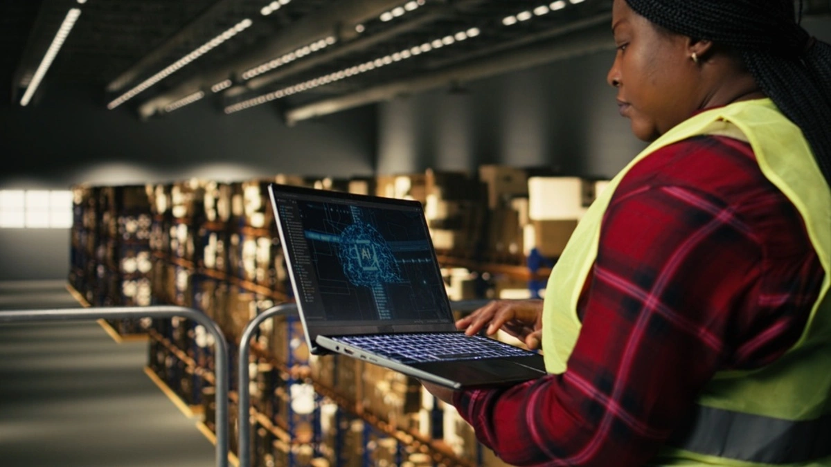 Female warehouse worker using a laptop with an AI tool running the logistics of the warehouse.
