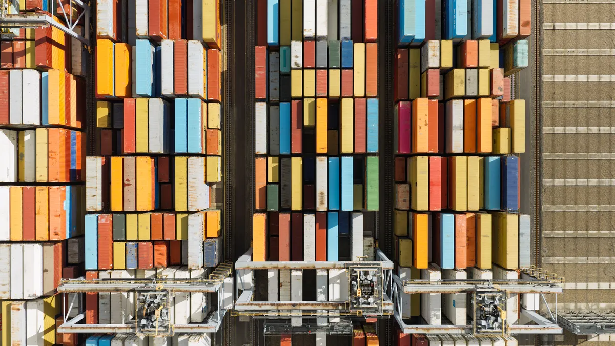 Aerial shot of stacked shipping containers in a shipping yard.