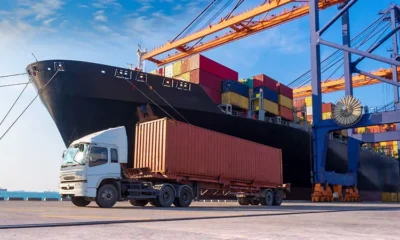 Freight ship docked in a harbour with a freight truck preparing to pick up the cargo.