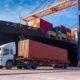 Freight ship docked in a harbour with a freight truck preparing to pick up the cargo.