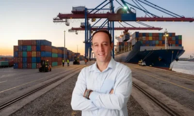 Roy Alves posing in a shipping yard in front of a freight ship.