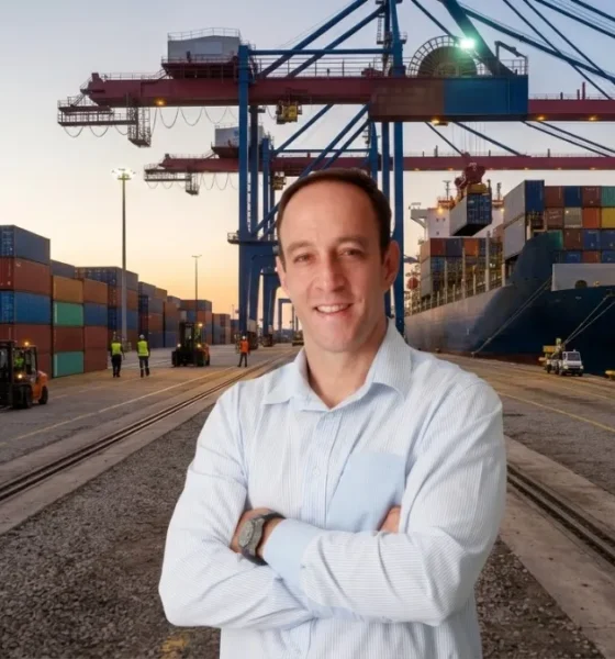 Roy Alves posing in a shipping yard in front of a freight ship.