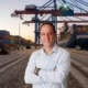 Roy Alves posing in a shipping yard in front of a freight ship.